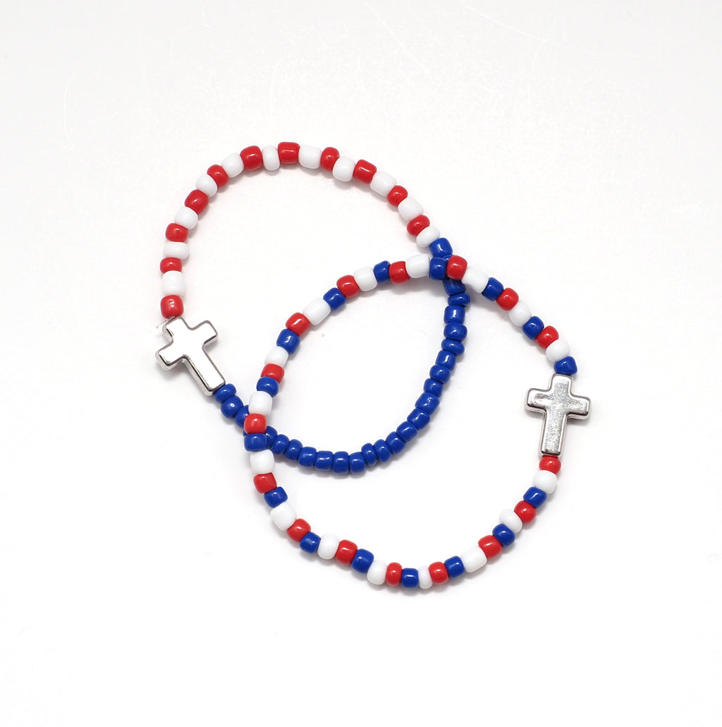 Seed bead stretch bracelet in red, white, and blue. Accented with a silver cross. 